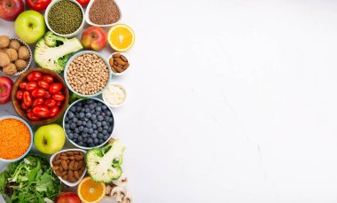 Sağlıklı yaşam tarzı, dengeli gıda, beslenme, temiz yemek kavramı. Beslenme için taze malzemeler, sebzeler, meyveler, fındıklar, beyaz masada kilo vermek için et. Sağlıklı arkaplan, üst görünüm.