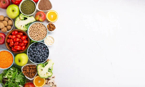 Sağlıklı yaşam tarzı, dengeli gıda, beslenme, temiz yemek kavramı. Beslenme için taze malzemeler, sebzeler, meyveler, fındıklar, beyaz masada kilo vermek için et. Sağlıklı arkaplan, üst görünüm.