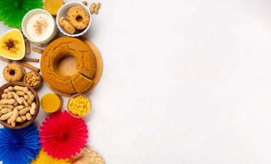 Junina Yaz Festivali Karnavalı konsepti. Brezilya hasır şapkası, Mısır keki, fıstık ve beyaz arka planda renkli bayraklar, üst manzara. Tebrik Kartı, Davetiye veya Tatil Posteri Tasarımı