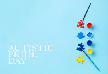 Otistik Gurur Günü veya Dünya Otizm Farkındalık Günü konsepti. Bulmacalar, otizm spektrum bozukluğu farkındalığının sembolü ve mavi arka planda renkli boyalar. Üst görünüm, alanı kopyala.