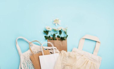 Uluslararası plastik poşetsiz gün konsepti. Üzerinde yaz çiçekleri olan yeniden kullanılabilir kağıt torba mavi arka planda tekstil pamuk ağ torbaları. Sürdürülebilir Ekoloji yaşam tarzı. Plastiğe hayır de Yeşile git Doğayı kurtar. 