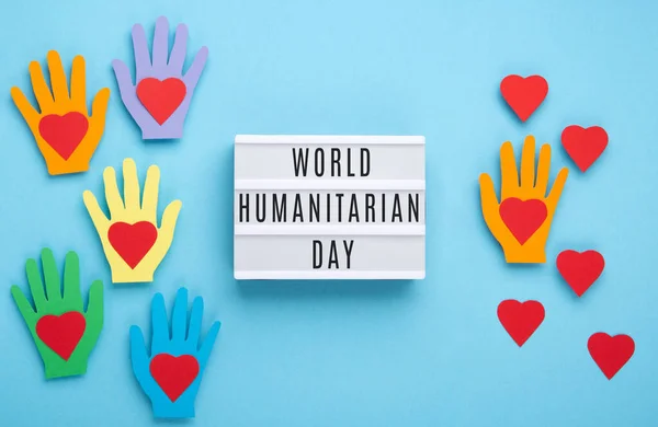 World Humanitarian Day Concept. Tolerance, kindness, cooperative, friendship, charity, humanitarian aid day concept. Colorful hands on blue background, copy space, top view.