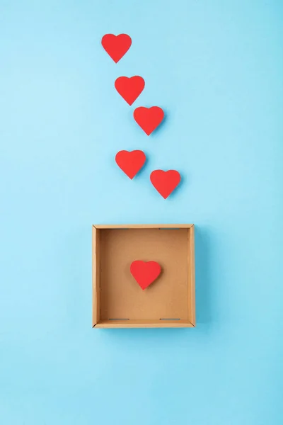 World Humanitarian Day Concept. Tolerance, kindness, cooperative, friendship, charity, humanitarian aid day concept. Red Hearts and donation box on blue background, copy space, top view.