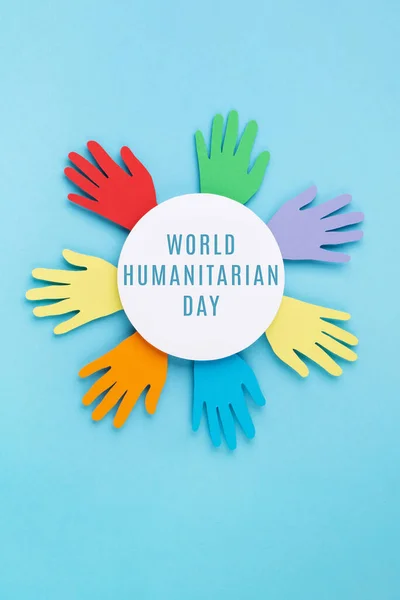 World Humanitarian Day Concept. Tolerance, kindness, cooperative, friendship, charity, humanitarian aid day concept. Paper Hands on blue background, copy space, top view.