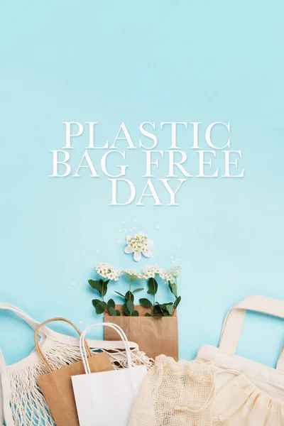 国际塑料袋免费日的概念 可重复使用的纸袋 夏季花卉 纺织品棉网袋蓝色背景 可持续生态生活方式 对塑料说不去绿色拯救自然 免版税图库图片