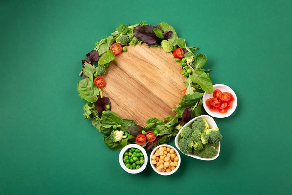 Vegetarian and vegan diet month in january called Veganuary. Variety of vegan, plant based protein food, healthy raw vegetables. Top view on green background.
