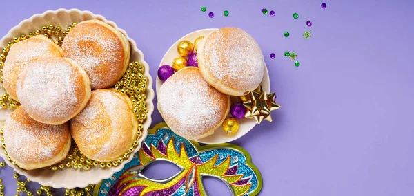 过节的甜甜圈与狂欢节的面具和紫色 绿色装饰紫色背景 假日派对邀请 贺卡概念 图库图片