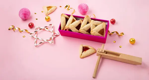 传统自制的哈曼曲奇饼 狂欢节面具 吵闹者 甜糖果和粉红背景的节日派对装饰 纯正庆祝犹太人节日的概念 — 图库照片