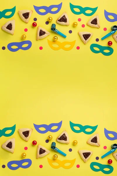 巧克力蘸着哈曼曲奇饼 狂欢节面具 吵闹者 甜糖果和黄色背景的节日派对装饰 俯瞰全景 纯正庆祝犹太人节日的概念 图库图片