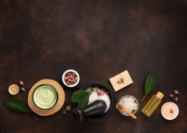 Tuz fırçalı cilt bakımı ürünleri, koyu ahşap arka planda taze yeşil yapraklar. Doğal çevre dostu güzellik, cilt bakım ürünleri, organik kozmetik konsepti. Üst görünüm, alanı kopyala.