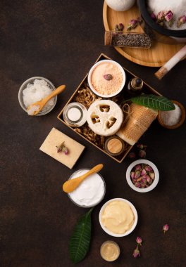 Tuz fırçalı cilt bakımı ürünleri, koyu ahşap arka planda taze yeşil yapraklar. Doğal çevre dostu güzellik, cilt bakım ürünleri, organik kozmetik konsepti. Üst görünüm, alanı kopyala.