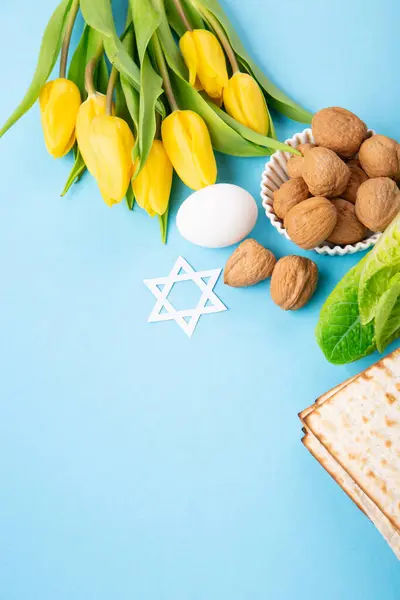 ユダヤ人の休日マツァマッツァ ユダヤ人の休日のパン クルミ 青いテーブルの上に黄色のチューリップの花と過越の挨拶カードの概念 Seder Pesach春休みの背景 コピースペース ストック写真