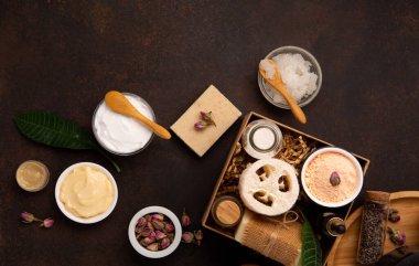 Tuz fırçalı cilt bakımı ürünleri, koyu ahşap arka planda taze yeşil yapraklar. Doğal çevre dostu güzellik, cilt bakım ürünleri, organik kozmetik konsepti. Üst görünüm, alanı kopyala.