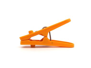 Plastic clothes pin isolated on white background. Close up of orange color clothes peg.