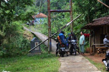 Sukabumi, Batı Java, Endonezya 'da sabah üstü motosikletli köprüden geçen asma köprü. Geleneksel altyapı binaları.