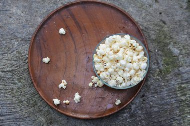 Tahta tabanlı cam bir kapta patlamış mısır. Kızartma tavasında patlamış mısır yapma süreci. beyaz patlamış mısır.