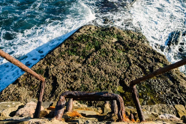 Iron ladder rusted by salt water, near a wall in the sea