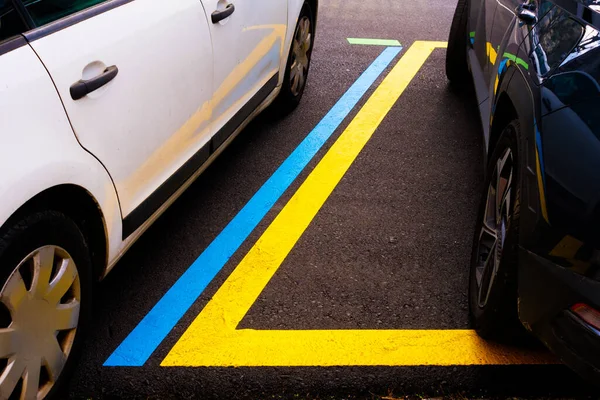 Blue and yellow lines to delimit paid car parks zone in lot.