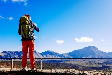 Tenerife, İspanya - 10 Ocak 2022: Genç maceraperest bir adam dağlık bir arazinin fotoğraflarını çeker