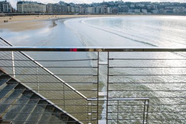 Metal fence and handrails on an outdoor staircase near the sea.