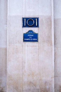 Bir beton duvarın arkasında Fransa, Paris 'teki Champs-Elyses Caddesi adında bir plaket var.. 