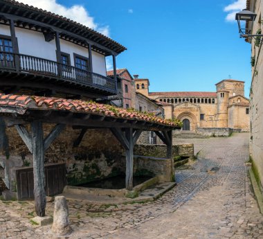 Santillana del Mar, İspanya 'da arka plandaki bir binaya doğru giden bir kaldırım taşı caddesi. Tarihi mimari ve geleneksel kaldırım taşları geçmişteki kasabalara bir göz atıyor..