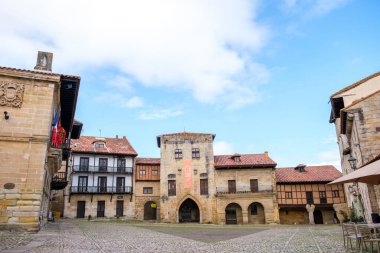 Cantabria 'nın Santillana del Mar kentindeki bir avluda merkezde önemli bir saat kulesi bulunuyor. İnsanlar hareket ettikçe sahne hareketleniyor..