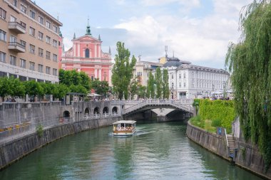Turist tekneleri Ljubljana Nehri boyunca şehir merkezinden geçiyor..