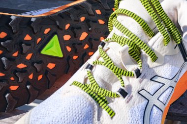 Valencia, İspanya - 6 Mart 2024: Bir ahşap bankta el değmemiş bir çift Asic ayak izi ayakkabısına yakın çekim.