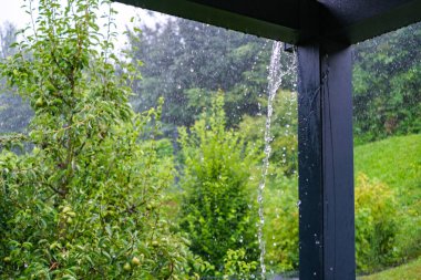 Yağmur suları çatıdaki oluklardan verandaya dökülüyor..