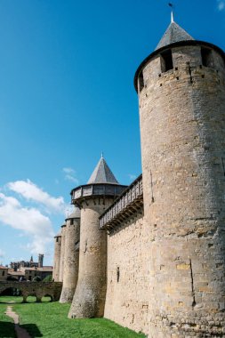 Castillo de Carcassonne 'un büyüleyici mimarisini keşfedin, yüksek taş duvarları ve kulesiyle, yemyeşil çimenler ve parlak mavi gökyüzü ile çevrili. Tarih aşıkları ve gezginleri için mükemmel bir yer..