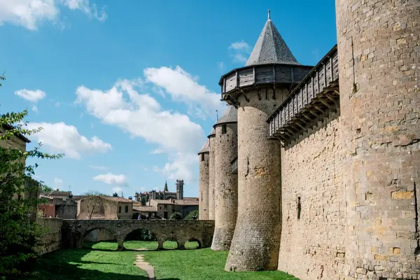 Castillo de Carcassonne 'un göz kamaştırıcı mimarisine hayranlık duyun, yüksek duvarları ve konik çatıları, parlak mavi gökyüzü ve yeşillik ile çerçevelenmiş, bu tarihi kalenin güzelliğini gözler önüne seriyor..