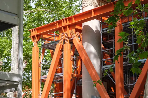 Kalın çelik iskeleler restorasyon sırasında tarihi bir yapıyı güvenli bir şekilde tutuyor. Çevresini saran yemyeşil ağaçlar doğa ve mimarinin uyumlu bir karışımını oluşturarak takım çalışmasını ve ilerlemesini ön plana çıkarıyor..