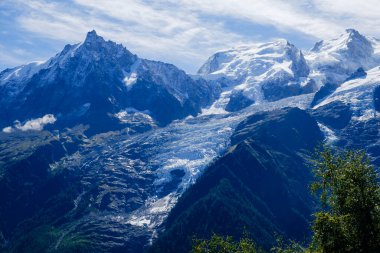 Mont Blanc 'ın yamaçlarından akan dramatik buzullar, açık mavi gökyüzünün altında yükselen dağlarla çevrilidir. Bu çarpıcı manzara Alpler 'in sakin ama güçlü manzarasını vurgular..