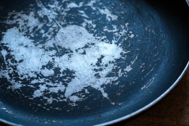 Eski bir tavanın, bozulmakta olan yapışmaz yüzeyini ve çiziklerini gösteren yakın çekim görüntüsü, evcil bir mutfak ortamında yıllarca kullanıldığını yansıtıyor..