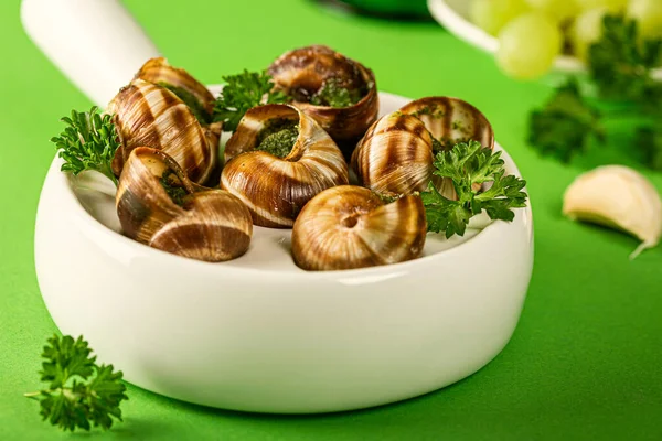 stock image Close up of Baked Bourgogne Escargot Snails with garlic herbs butter in ceramics pan on green background