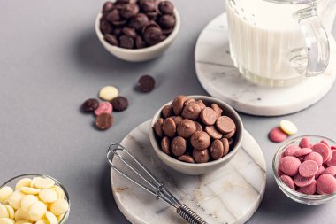 Sıcak çikolata pişirmek için gerekli malzemeler. Beyaz, süt, yakut ve sütlü koyu çikolata parçaları. Gri arka planda. Yüksek açı görünümü