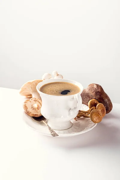 White porcelain vintage cup with mushroom coffee on white background. New Superfood Trend, selective focus, copy space