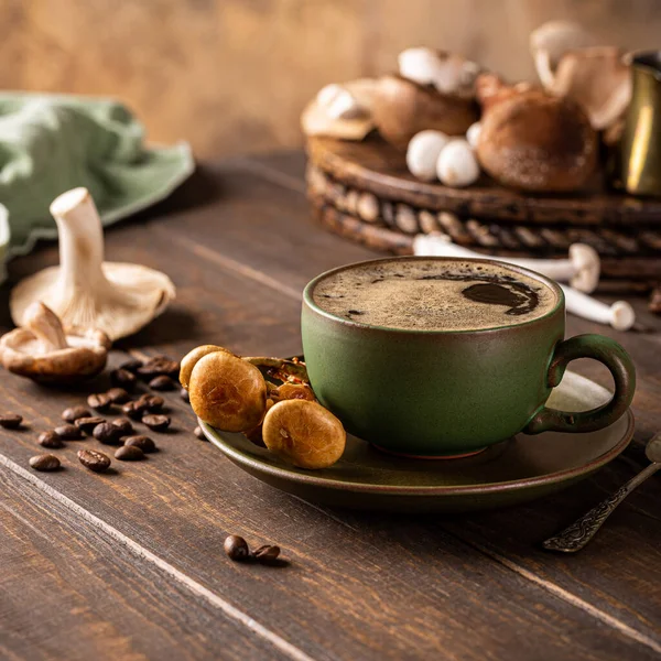 Trendy superfood mushroom coffee in green cup on wooden background. Healthy concept with copy space
