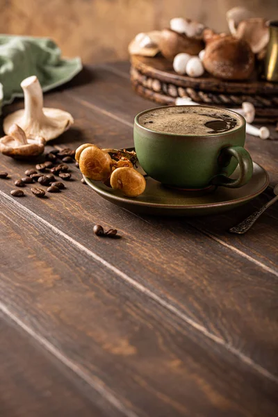 Trendy superfood mushroom coffee in green cup on wooden background. Healthy food concept with copy space, selective focus.