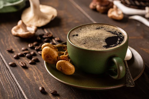 Coffee with mushrooms in green cup on wooden background. New Superfood trendy healthy concept with copy space, selective focus.