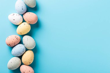 Easter quail eggs over blue background. Spring holidays concept with copy space. Top view