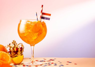 Summer coctail Aperol spritz in glass with Dutch event Kings day in background. National holiday Koningsdag on 27 aprilin the Netherlands. Holland culture concept with copy space