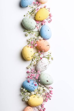 Easter quail eggs and springtime flowers over white background. Spring holidays concept with copy space. Top view