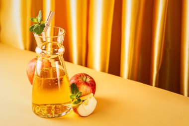 Bir sürahi taze elma suyu ve sarı arka planda organik elmalar. Fotokopi alanı ile sağlıklı içecek kavramı