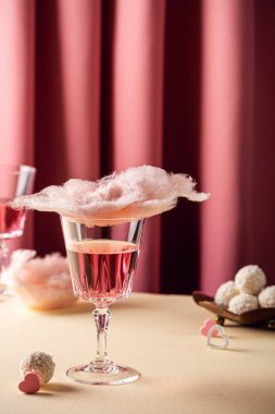 Sevgililer Günü kompozisyonu, cam tatları olan pamuk şeker pembe arka planda şampanya ve fotokopi alanı.