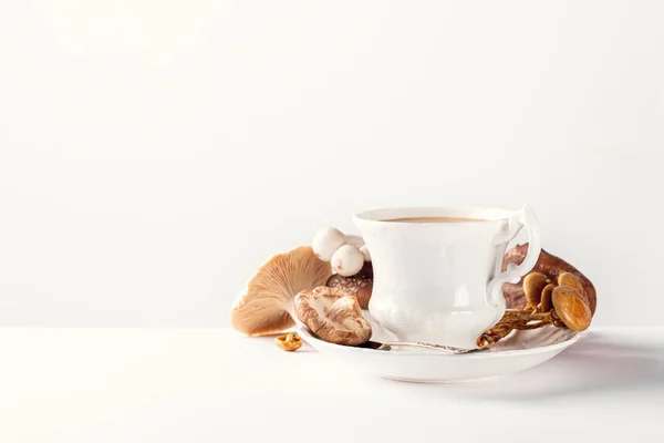 White porcelain vintage cup with mushroom coffee on white background. New Superfood Trend, selective focus and copy space
