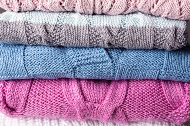 Masada temiz, yeni yıkanmış, düzgünce katlanmış kadın kıyafetleri yığını var. El yapımı zift renkli örgü arka planı