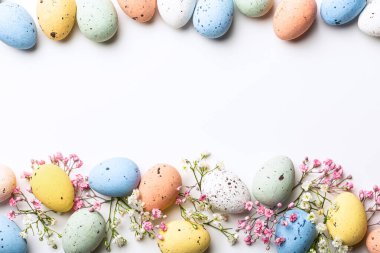 Easter quail eggs and springtime flowers over white background. Spring holidays concept with copy space. Top view