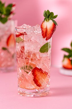 Ezilmiş buz, çilek ve pembe zemin üzerinde naneli taze limonata kokteyli. Yaz soğuk içecek konsepti